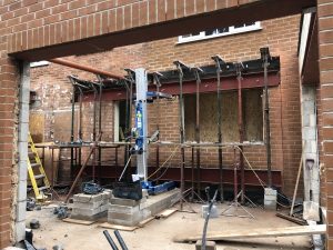 Steel Beams being supported by a genie lift and acrow props.